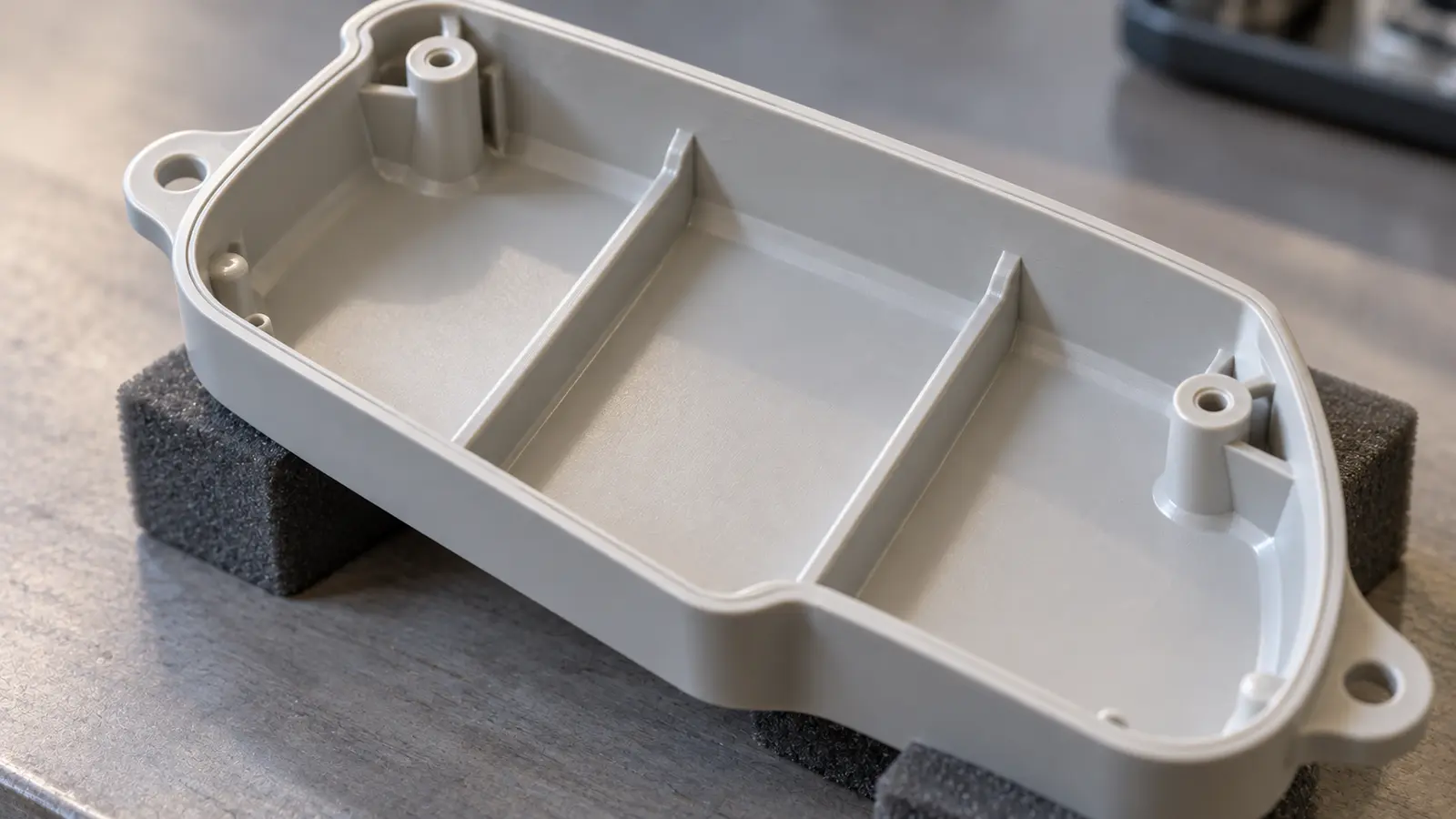 Underside of a molded plastic cover showing its wall, reinforcing ribs and screw bosses