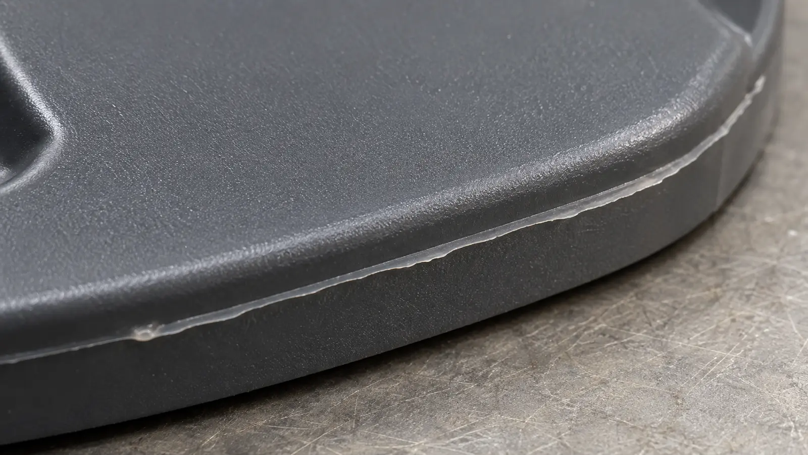 Close view of a thin plastic flash fin along the outer rim of a molded cover