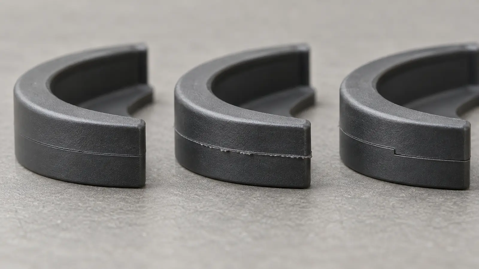 Three molded plastic part edges showing a fine parting-line seam, a thin flash lip, and a mismatch step