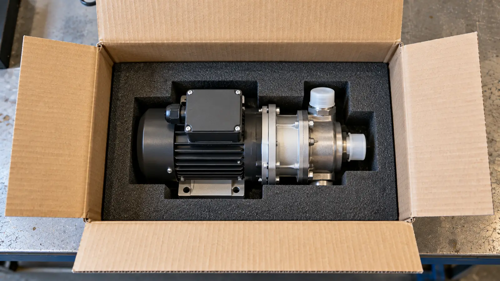 Assembled compact pump supported in a fitted foam insert inside an open plain shipping carton